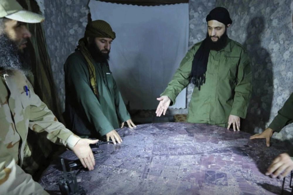 夏拉（右）曾經是極端組織蓋達的成員，日後成立的反抗組織也與蓋達關係密切，成為他與西方陣營往來時的重大阻礙，圖為他於2016年與下屬討論戰術以及局勢的畫面。（資料照片／美聯社）